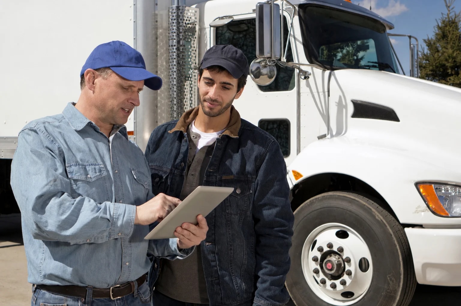 clean-truck-check-compliance-review Drivers reviewing California Clean Truck Check requirements beside a commercial truck.